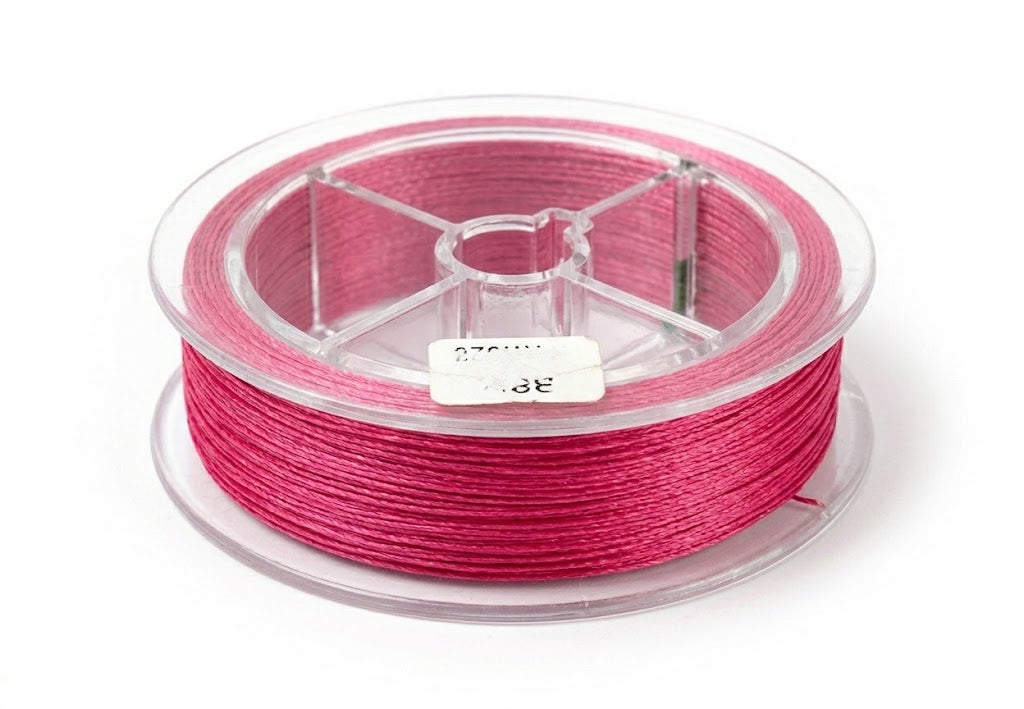 Une vue de studio nette et précise d'une bobine de fil de pêche tressé de couleur rose fuchsia vif, enroulée sur une bobine en plastique transparent, reposant sur un fond blanc pur.