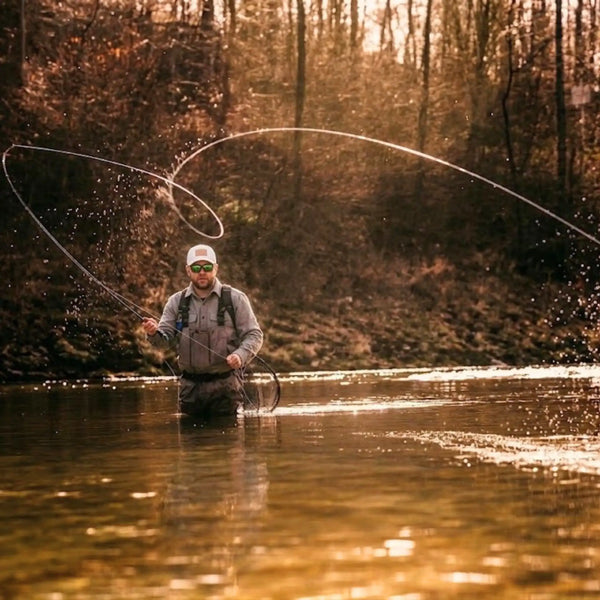 Fly fisherman in waders casting his line on a river, golden late-day light

